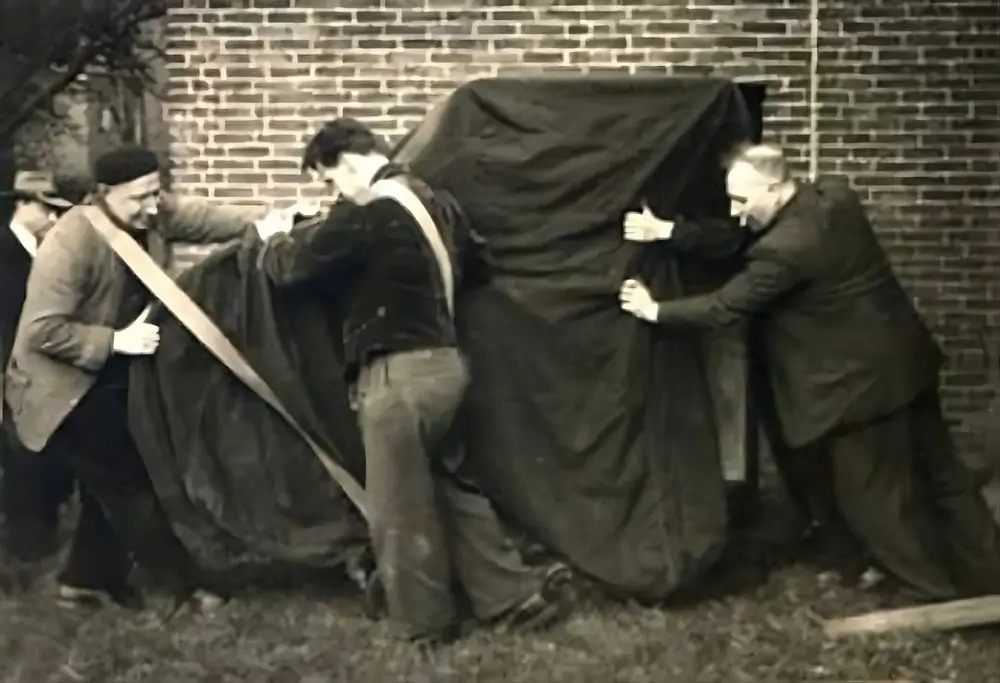 Verhuizers van Harteveld dragen een vleugel onder een dekkleed, archieffoto